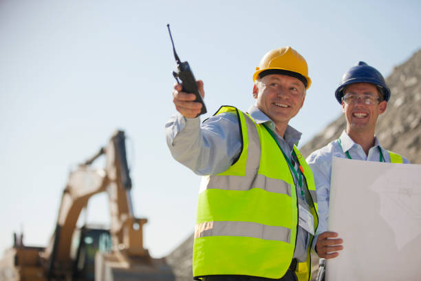 A construction foreman uses a durable two-way radio to coordinate with his team, demonstrating effective job site communication for improved safety and efficiency.