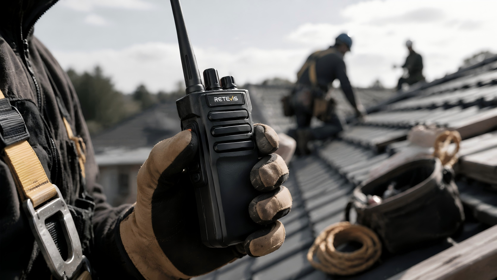Close-up of a roofer using a waterproof push-to-talk walkie-talkie with belt clip on a rooftop jobsite.