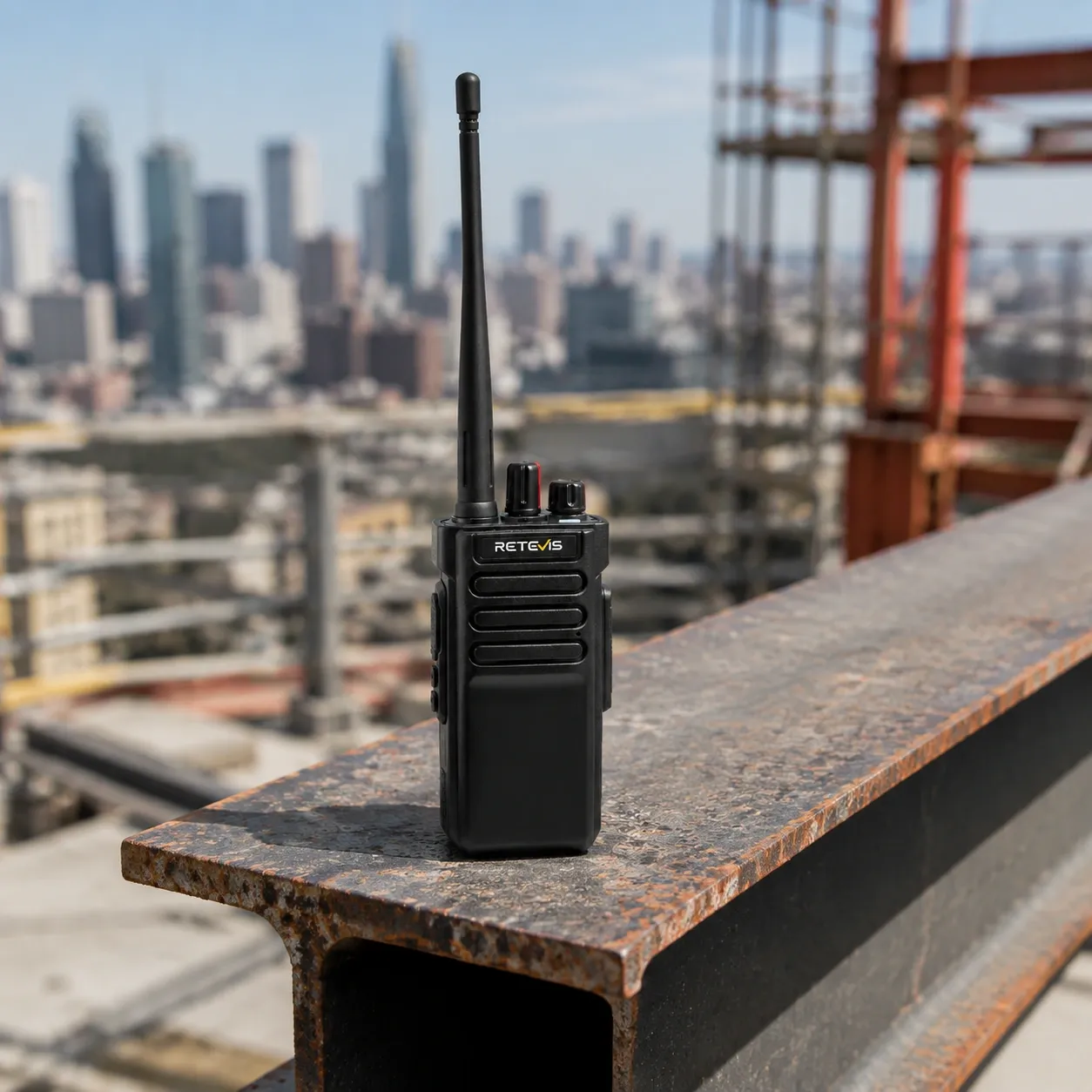 Close-up of a rugged industrial handheld radio with glove-friendly controls on a construction workbench